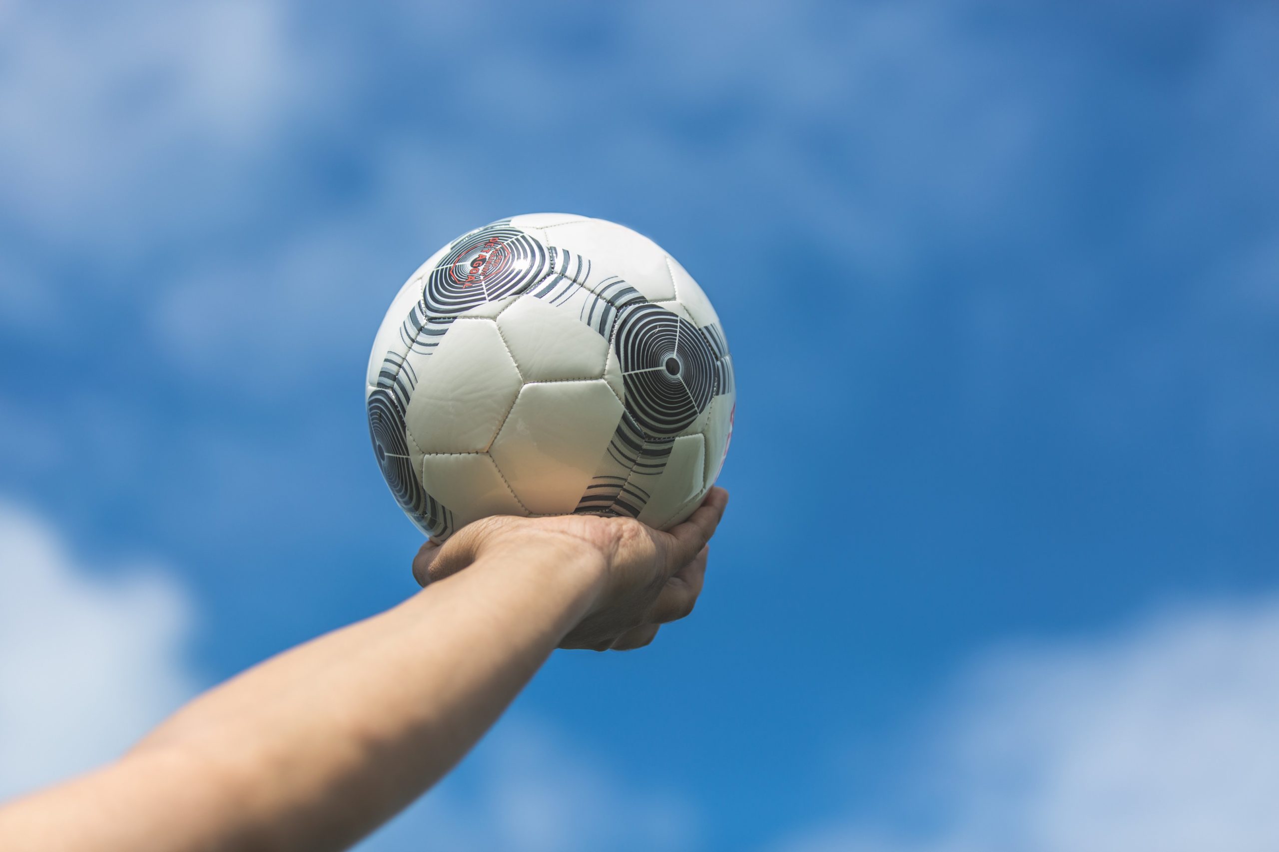 holding-out-soccer-ball-to-the-blue-sky